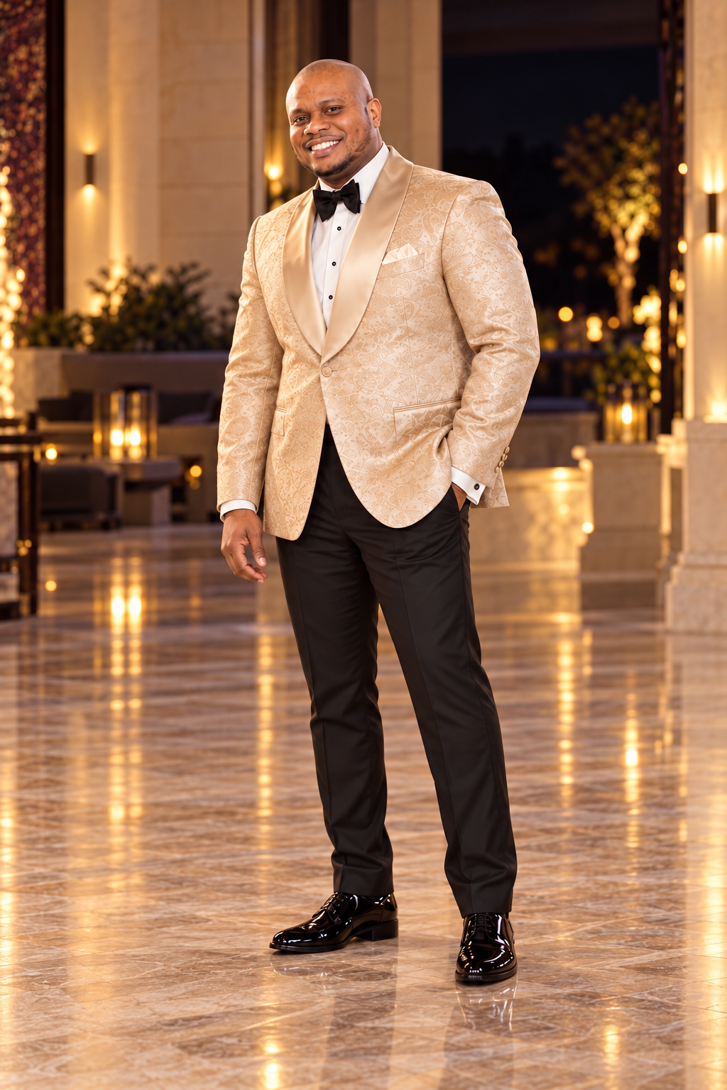 Igwe in a champagne brocade tuxedo with a black bow tie, standing full length